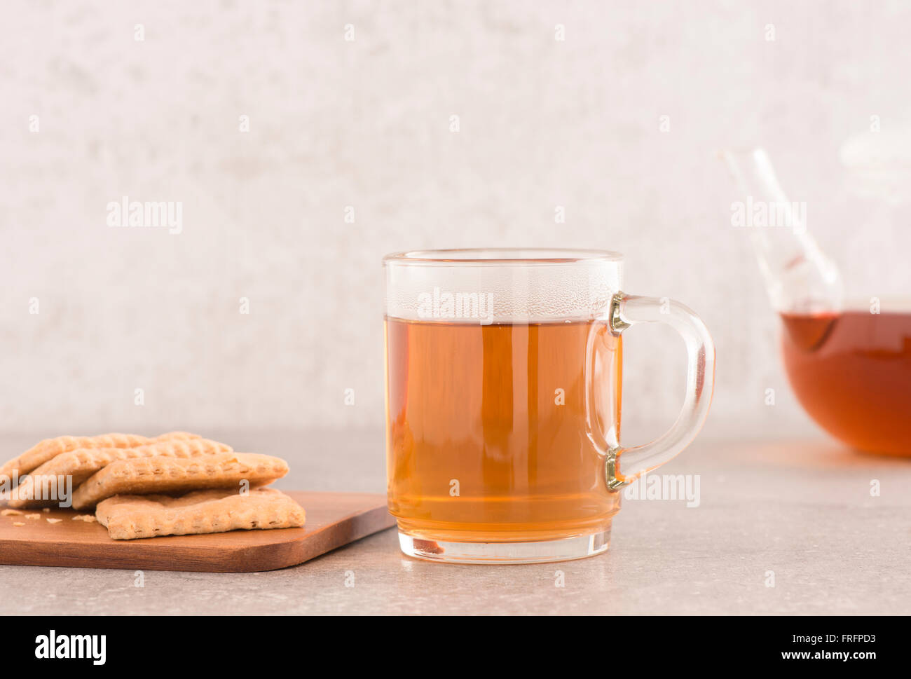Tee im Glaskrug und Kekse, Teekanne im Hintergrund. Essen-Stilleben. Moderne Küche mit Steintisch. Stockfoto