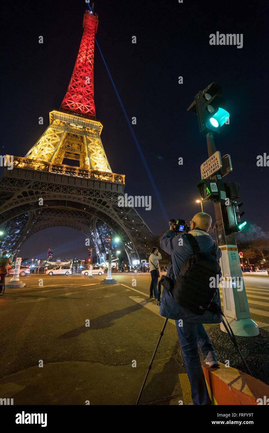 Paris, Frankreich. 22. März 2016. Ein Fotograf nimmt Bilder auf den Eiffelturm beleuchtet die belgische Flagge Farben nach Terror-Anschlägen in Brüssel, Belgien. Bildnachweis: David BERTHO/Alamy Live-Nachrichten Stockfoto