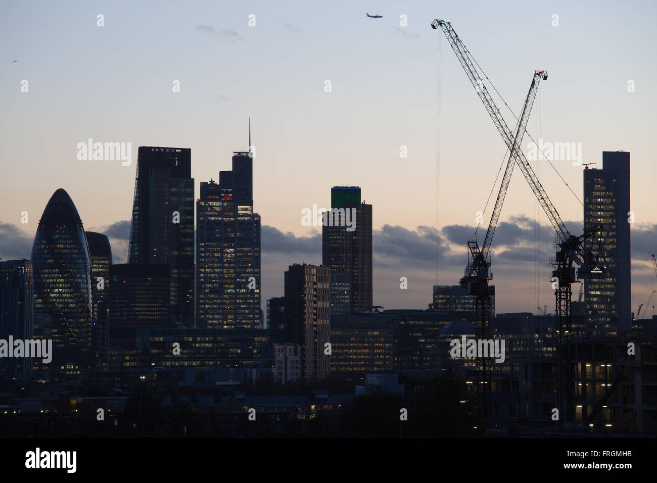 Blick auf die City of London, gesehen von Hackney, East London. Eine Ebene verläuft in den Himmel. Stockfoto