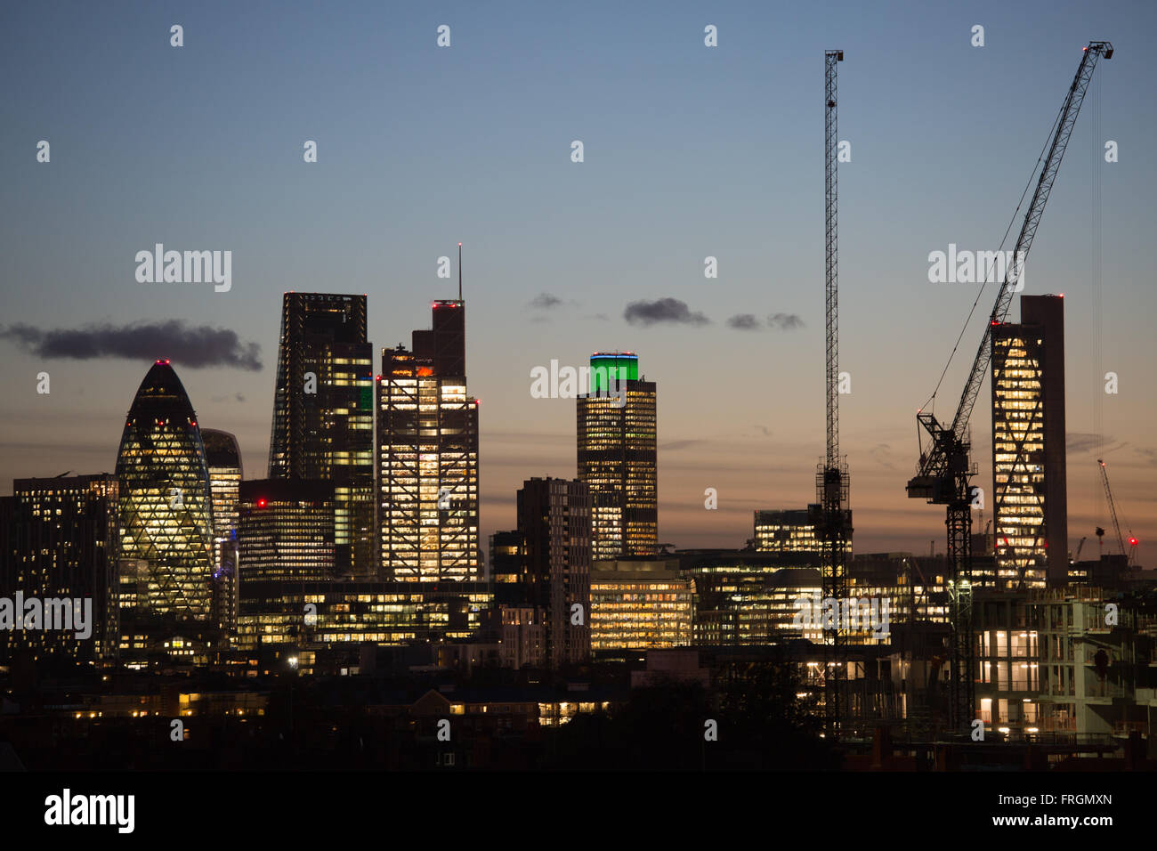 Die Sonne geht unter, auf der City of London und die Lichter sind an, gesehen von Hackney, East London. Stockfoto