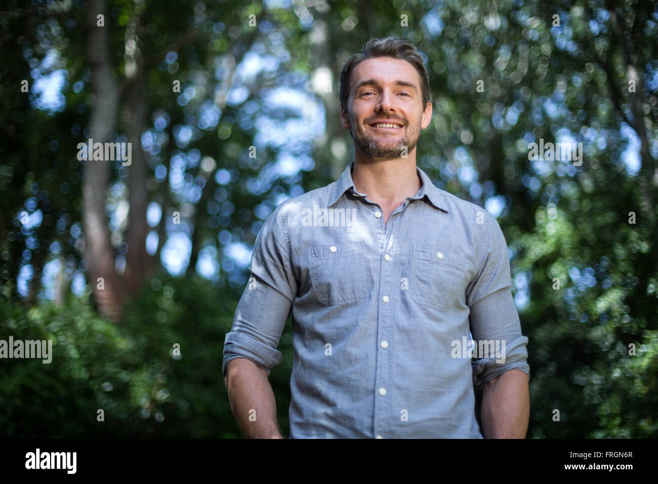 Porträt von glücklicher junger Mann gegen Bäume Stockfoto