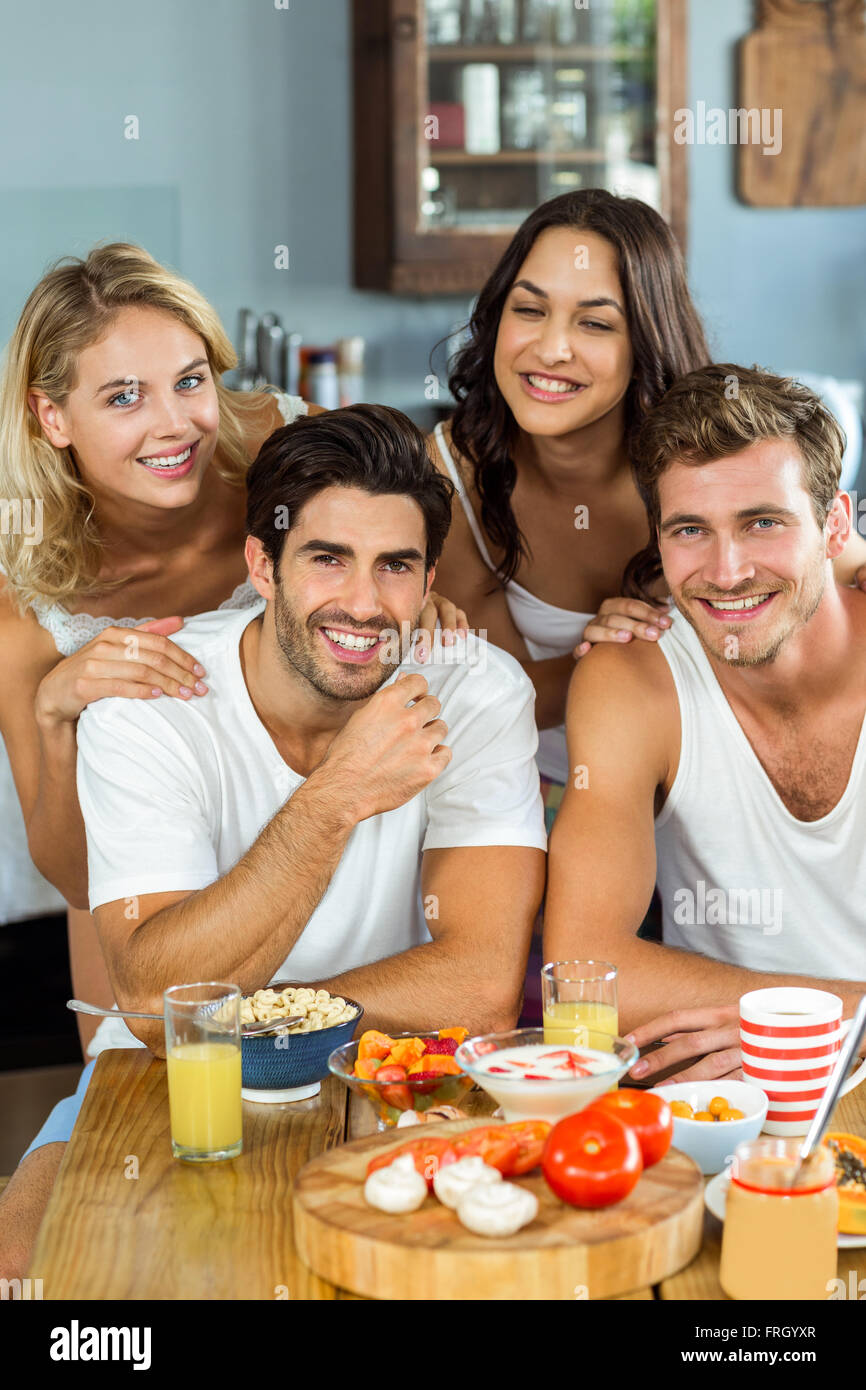 Lächelnde junge Paare am Frühstückstisch in der Küche Stockfoto