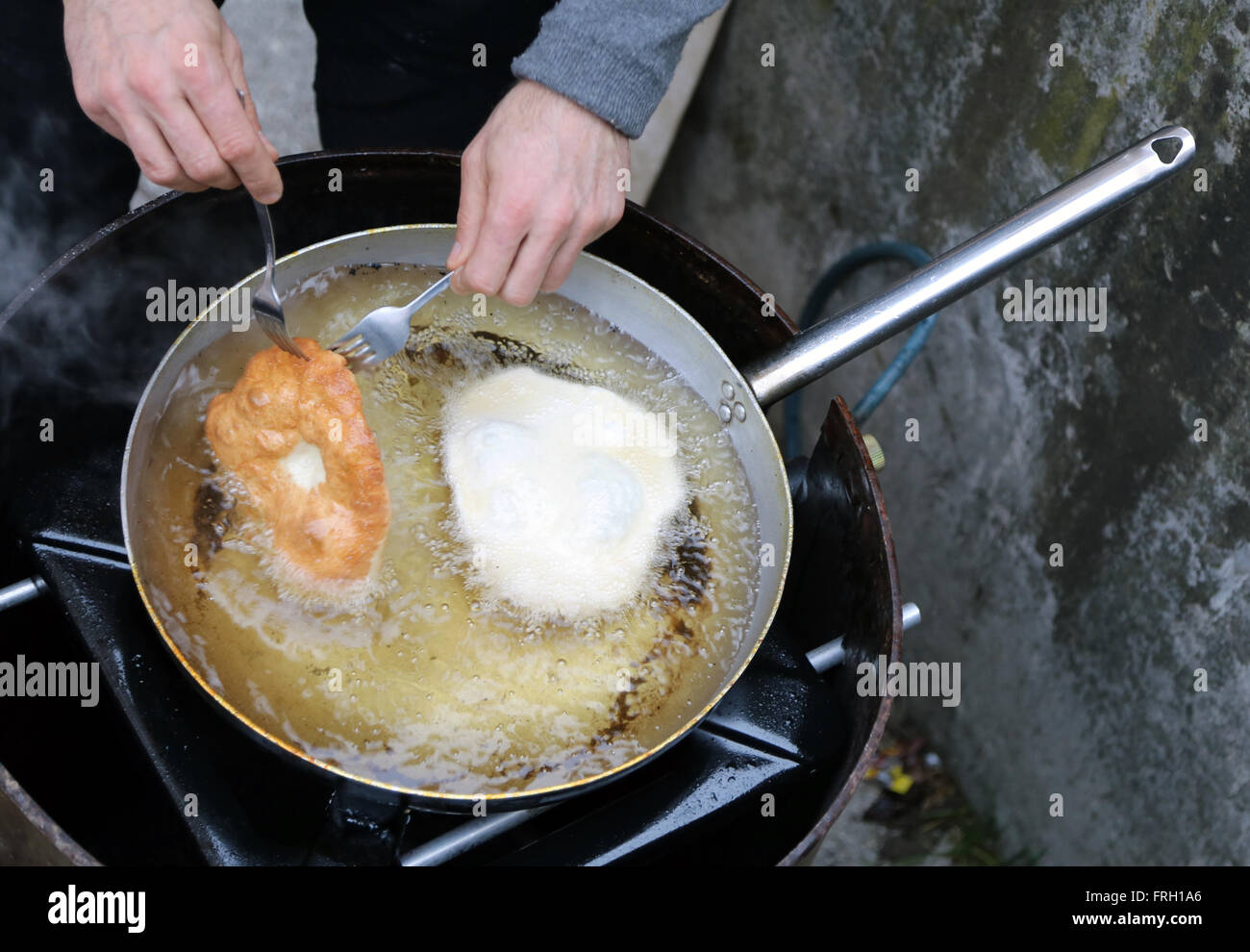 Koch, während er die leckeren Krapfen in kochendem Öl kochen Stockfoto