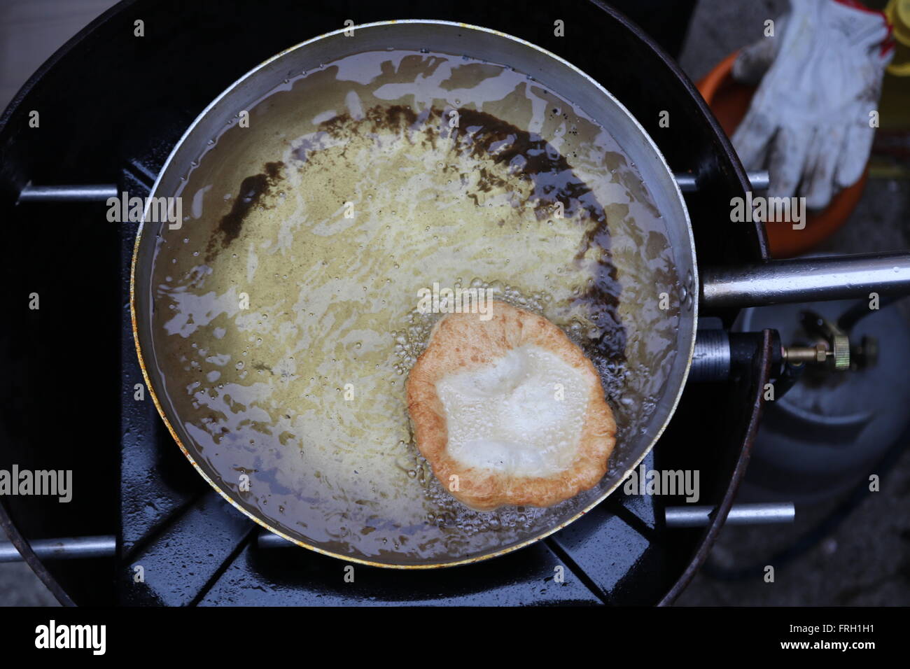 Hände zu kochen, während die große frittierte Krapfen Kochen eingetaucht in siedendem Öl in einem Topf Stockfoto