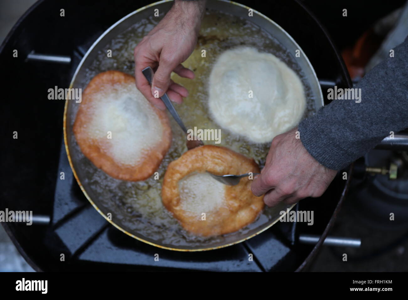 Kochen Krapfen eingetaucht in siedendem Öl in einen Aluminium-Topf Stockfoto