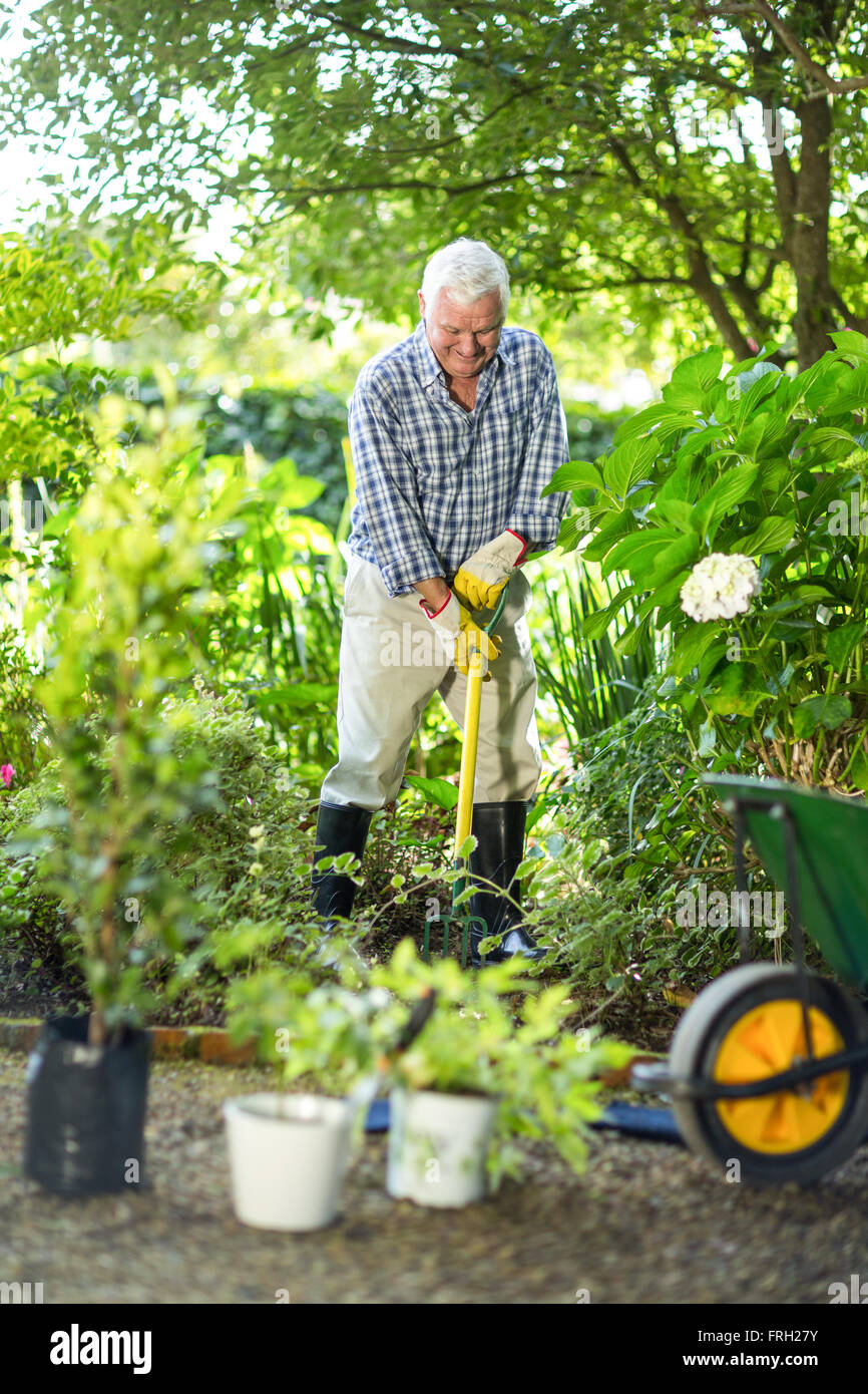 Senior woman über Rake im Garten Stockfoto