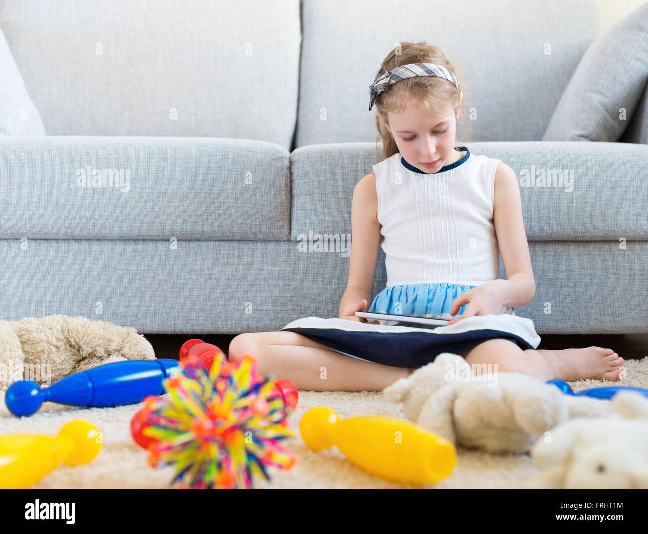 Es ist Zeit, um Ihre Spielzeuge zu bereinigen! Kleine Mädchen spielen mit Tablet-pc, wollen nicht die Reinigung zu tun. Stockfoto