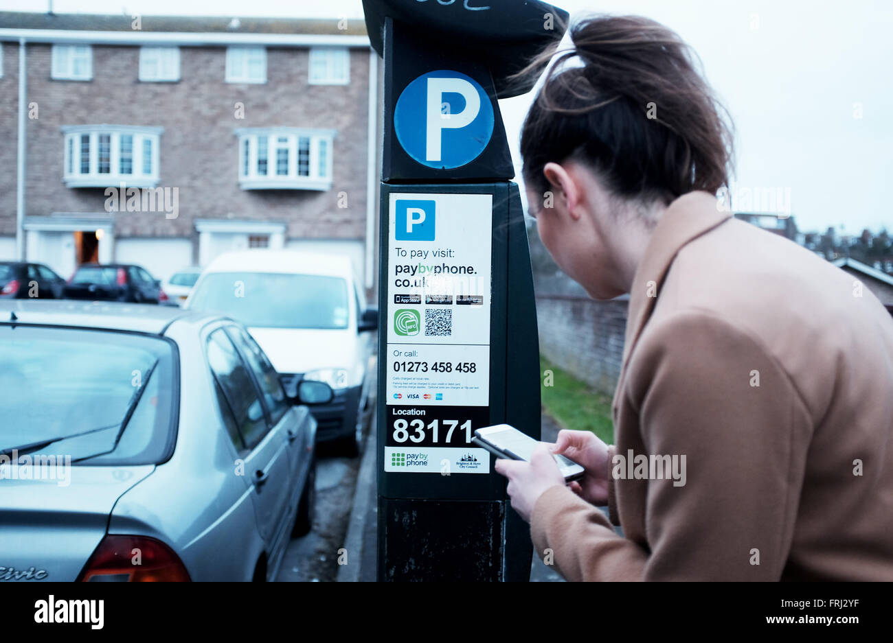 Junge Frau Autofahrer kauft einen Parkschein lösen mithilfe einer Smartphone-app in Brighton East Sussex UK Stockfoto
