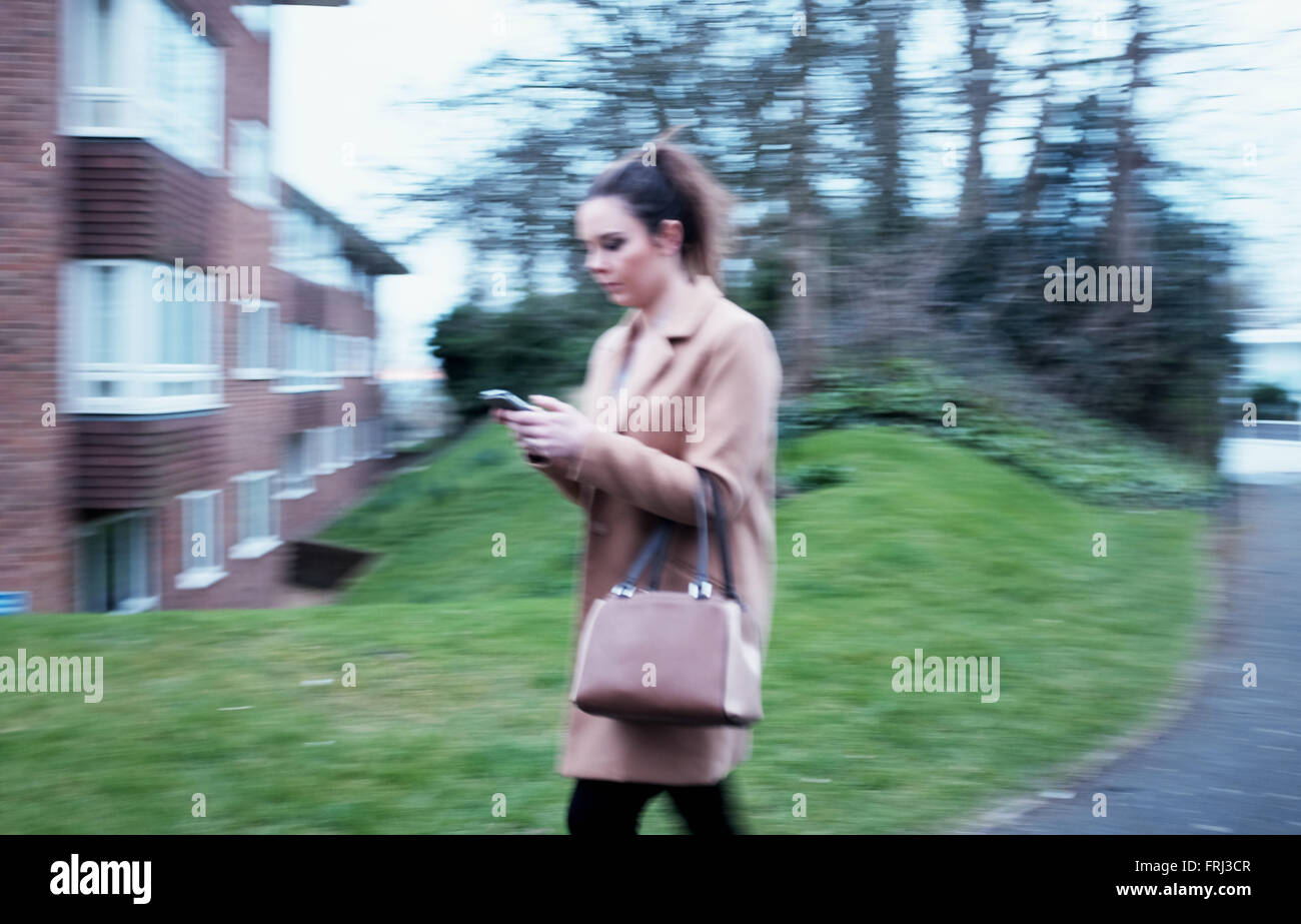 Junge Frau zu Fuß entlang auf ihre mobile smart phone Stockfoto