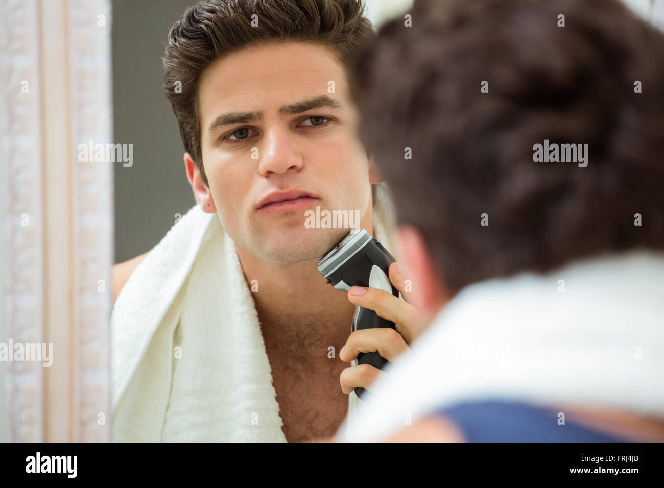 Junger Mann Rasieren mit trimmer Stockfoto