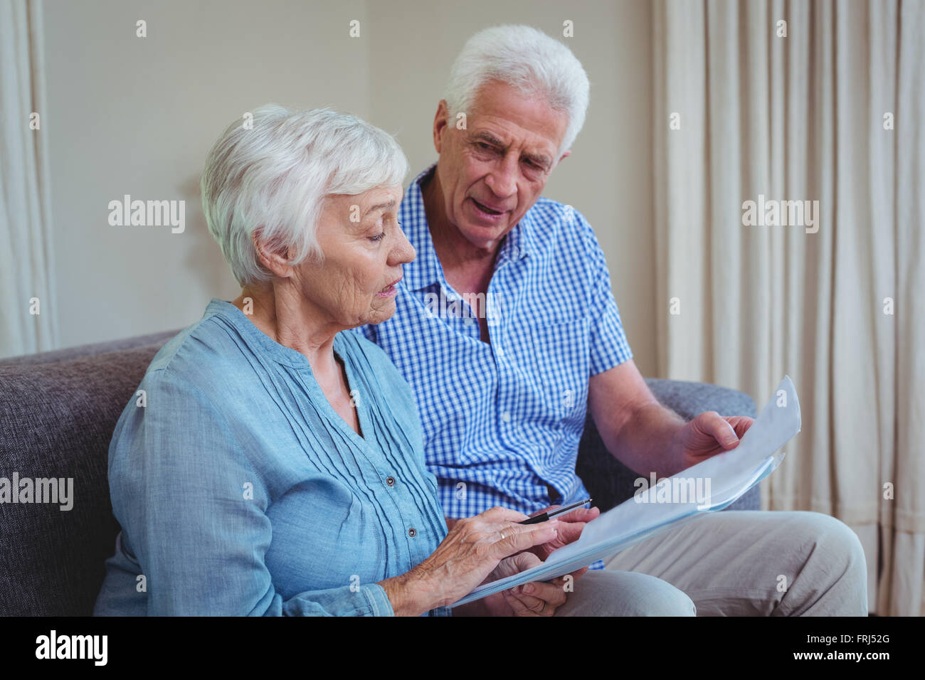 Älteres Paar mit Rechnungen sitzend auf sofa Stockfoto