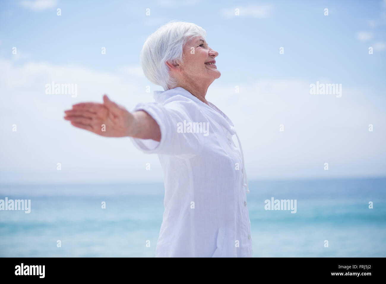 Ältere Frau lächelnd, während am Strand trainieren Stockfoto
