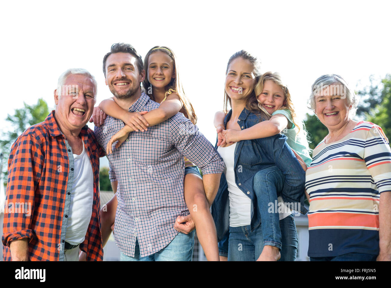 Glückliche Eltern tragen Mädchen bei den Großeltern im Hinterhof Stockfoto