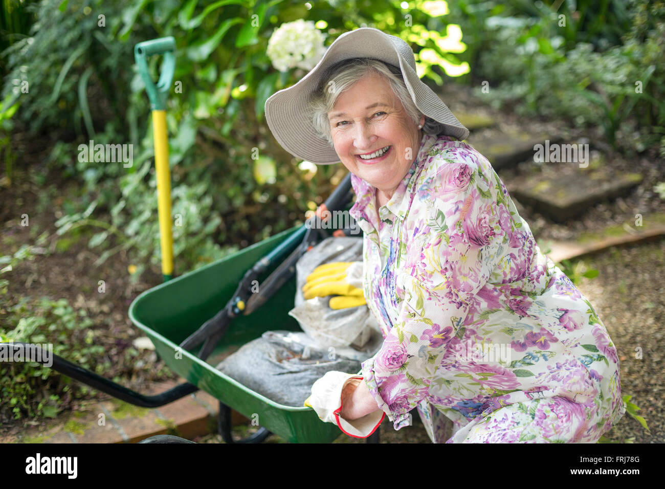 Portrait von senior Frau mit Schubkarre im Garten Stockfoto