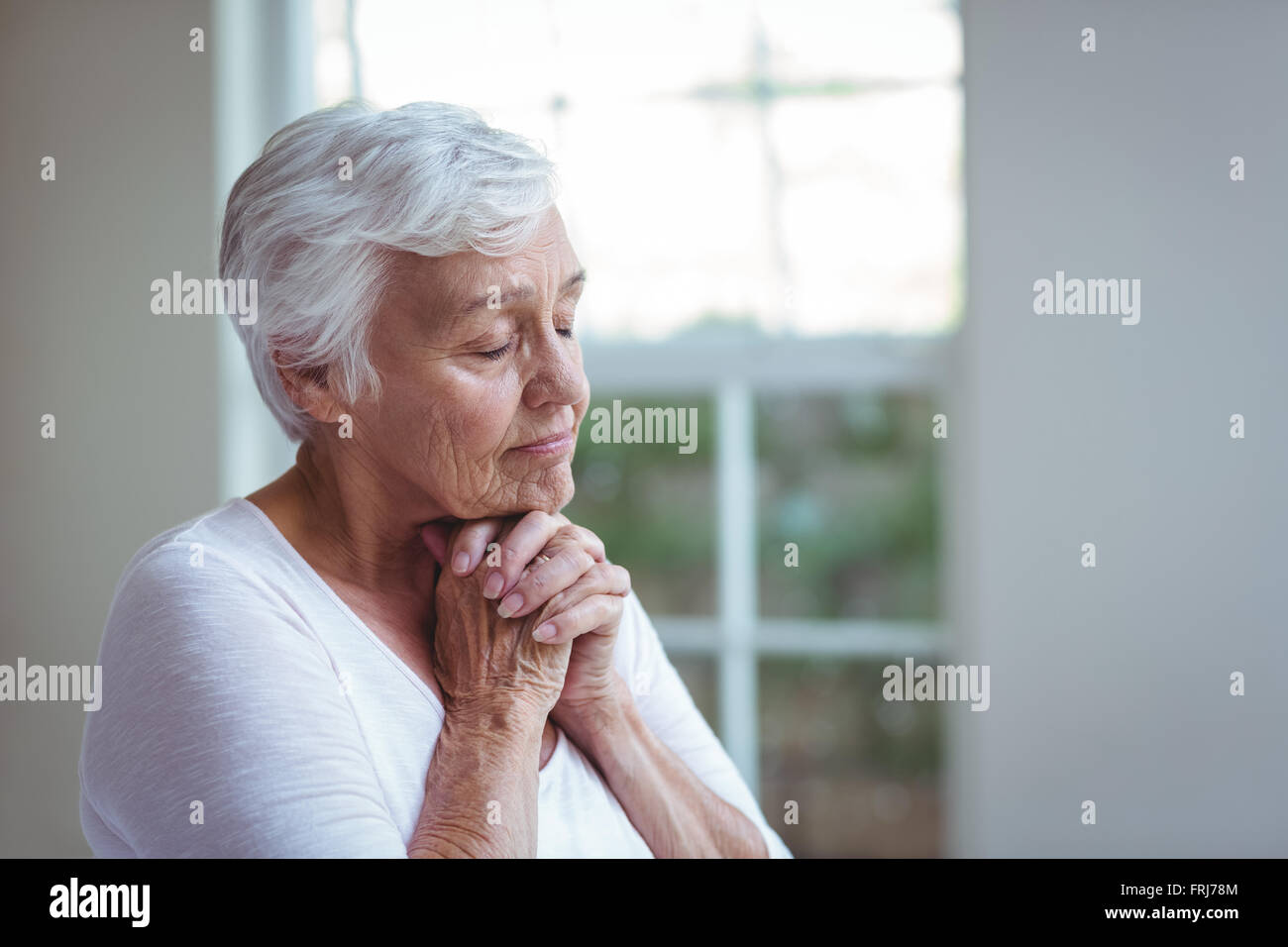 Ältere Frau zu Hause beten Stockfoto