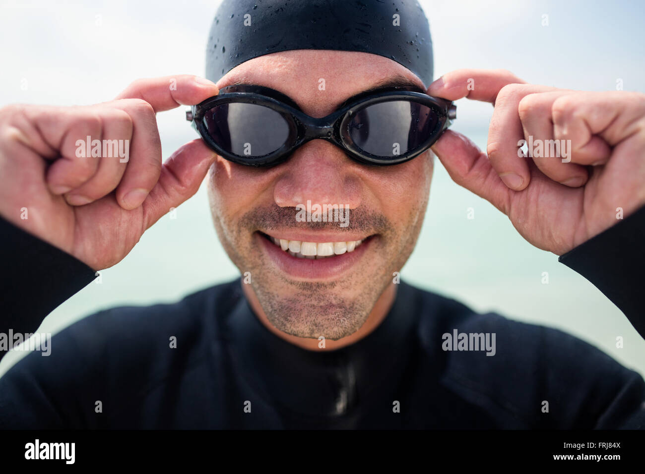 Junger Mann in Anzug und Schwimmbrille stehen am Strand. Stockfoto