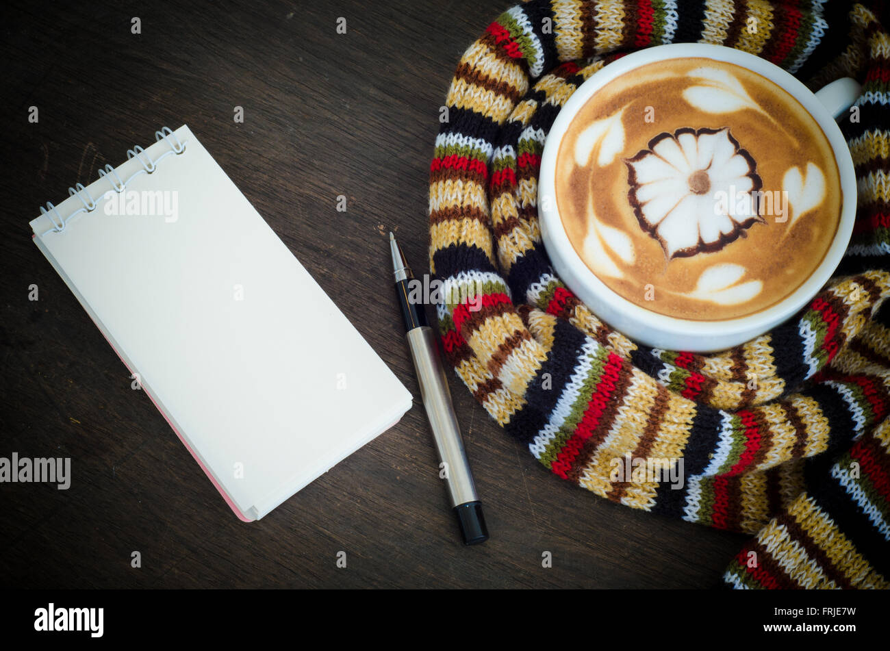 Tasse Kaffee umgeben das warme Schal und Hinweis-Buch Stockfoto