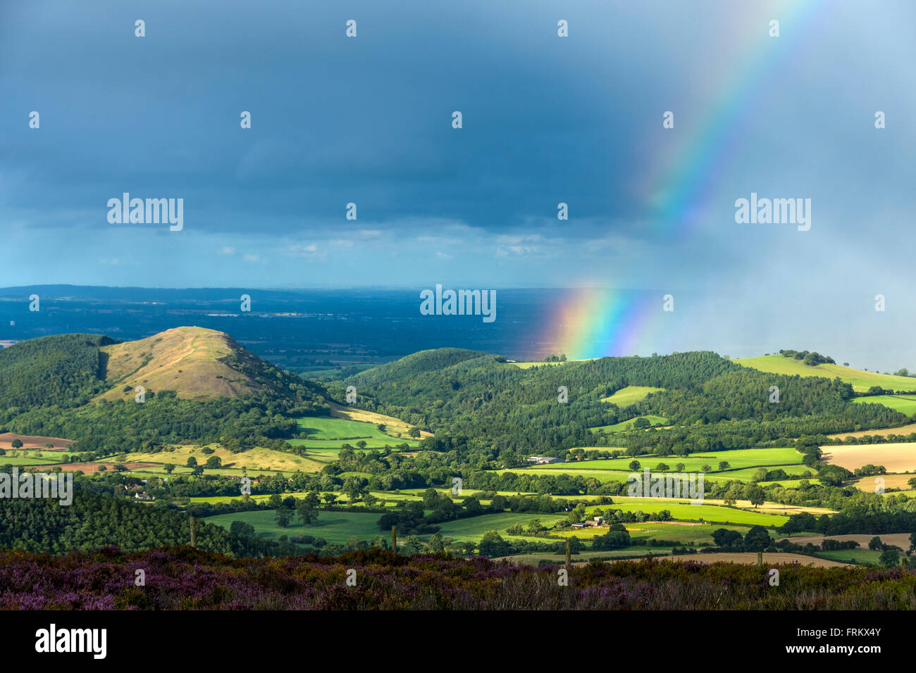Gewitter mit Regenbogen aus der Stiperstones Ridge in der Nähe von Snailbeach, Shropshire, England, UK. Earl es Hill in der Nähe von Pontesbury auf der linken Seite Stockfoto