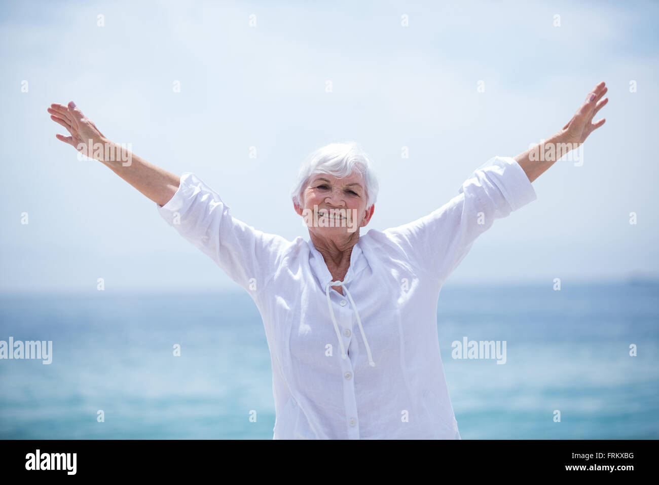 Happy senior Woman Arme ausgestreckt auf See Ufer Stockfoto