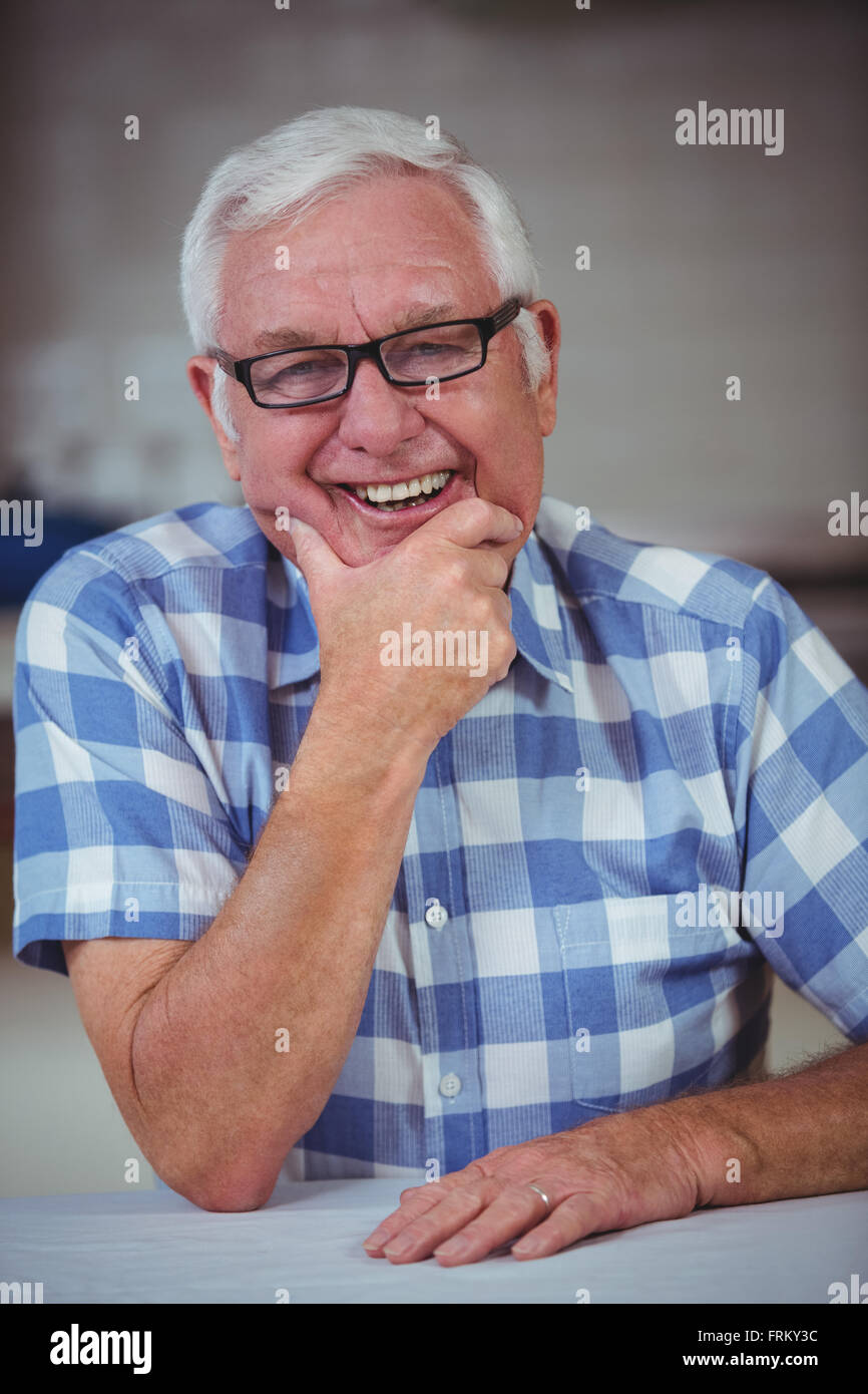 Fröhlichen senior Mann am Tisch Stockfoto