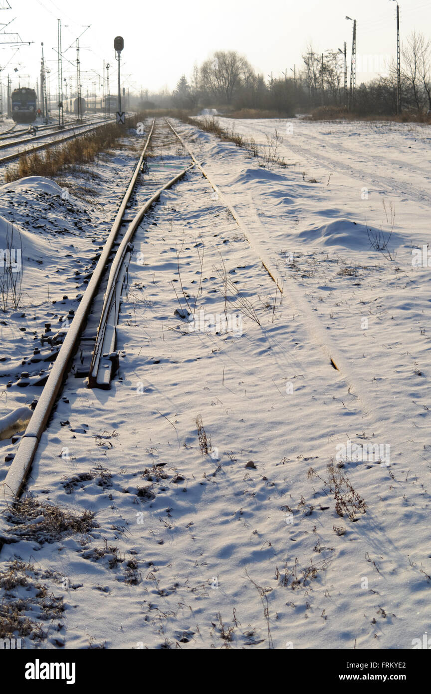 ungebraucht, Schnee bedeckte Schienen neben einer Eisenbahn an der sonnigen Wintermorgen Stockfoto