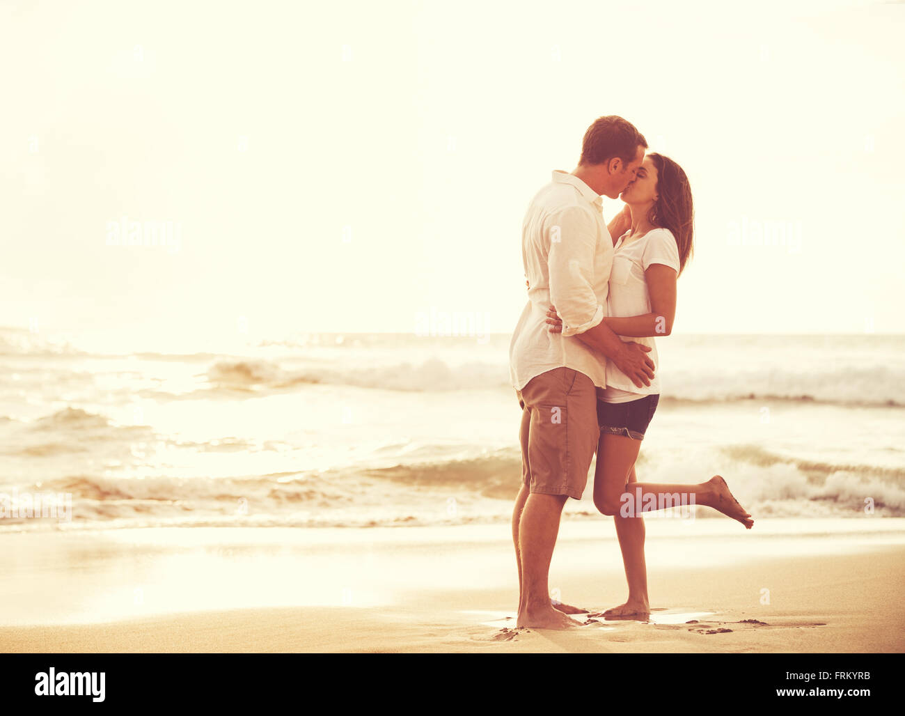Romantisches Brautpaar am Strand bei Sonnenuntergang. Frisch Verliebte im Urlaub. Stockfoto