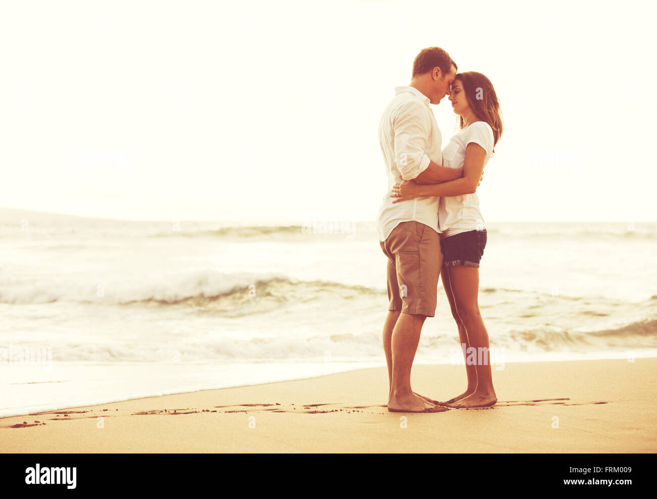 Romantisches Brautpaar am Strand bei Sonnenuntergang. Frisch Verliebte im Urlaub. Stockfoto