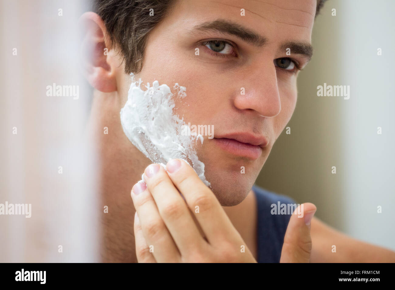 Junger Mann Rasierschaum im Gesicht anwenden Stockfoto