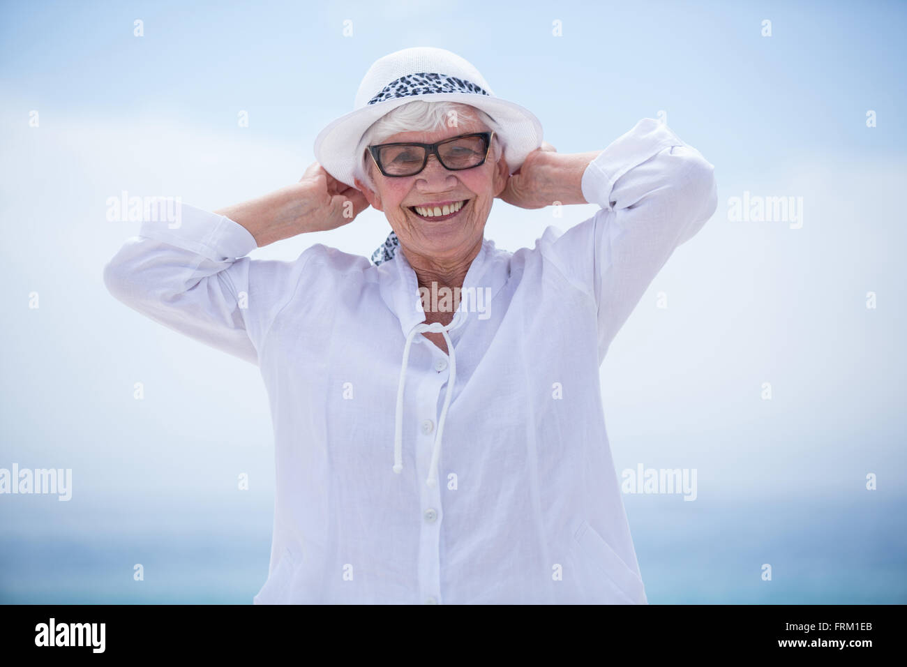 Fröhliche senior Frau am Strand gegen Himmel Stockfoto