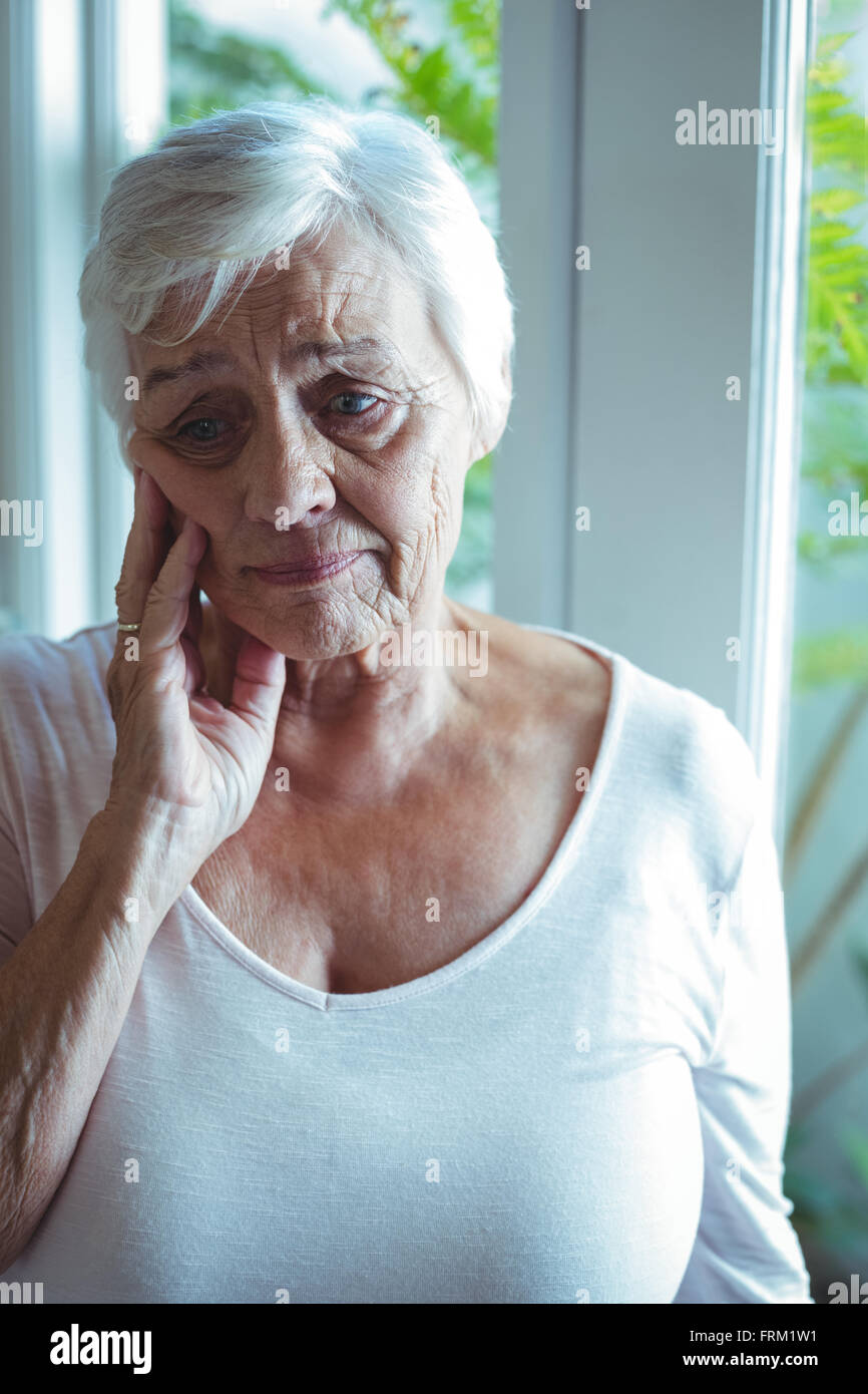 Nachdenklich senior Frau gegen das Fenster Stockfoto