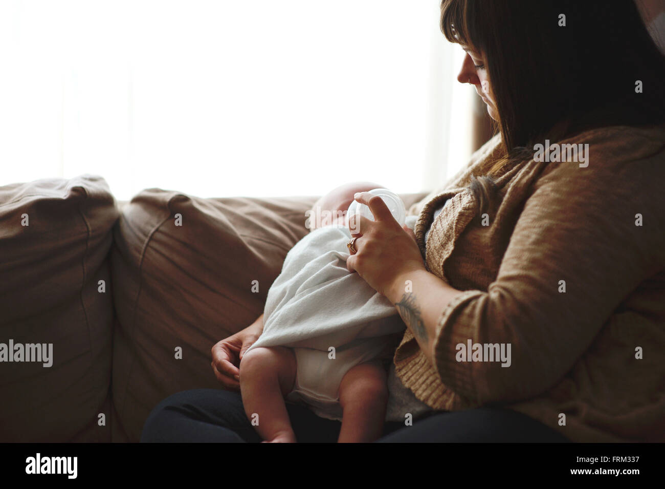 Mutter füttert Babyjungen eine Flasche sitzen an einem Fenster Stockfoto