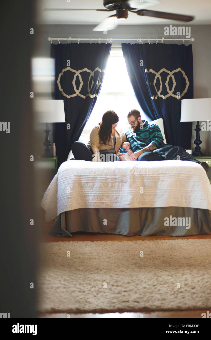 Neue Mutter und Vater mit Baby. Verlegung im Bett. Stockfoto