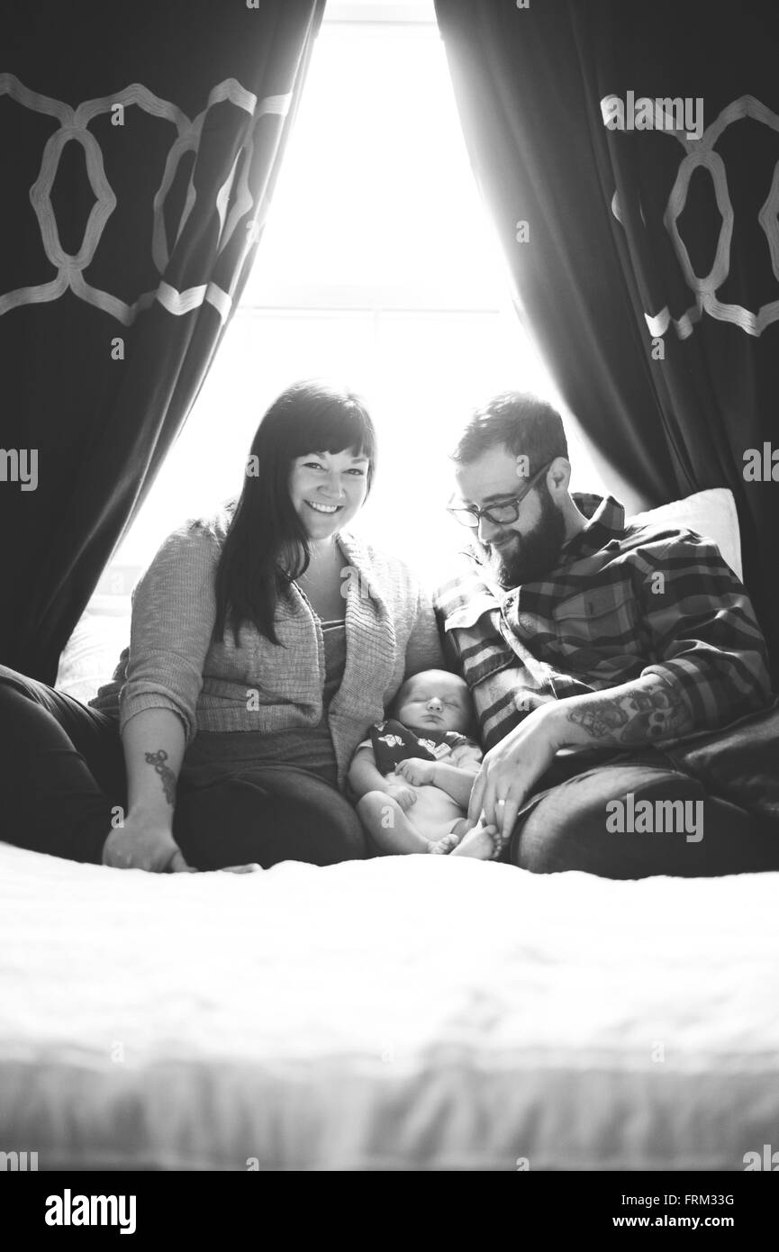 Neue Mutter und Vater mit Baby. Verlegung im Bett und lächelte. Stockfoto
