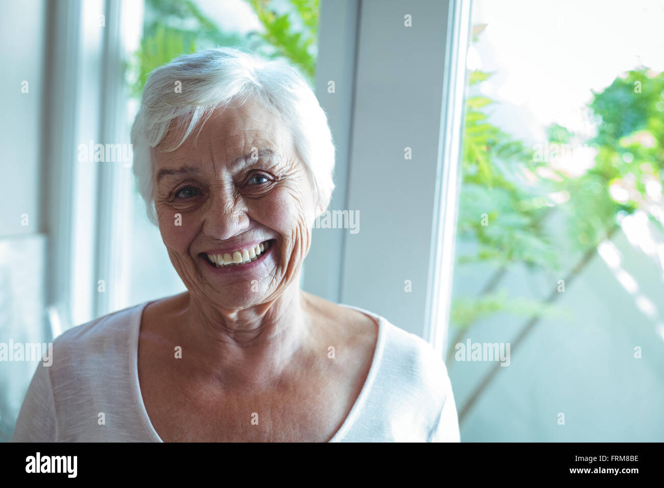 Porträt von senior Frau gegen Fenster Stockfoto
