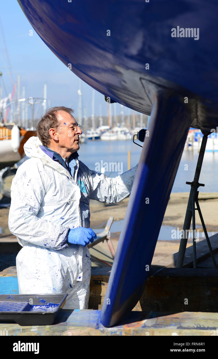 Der Bootsbesitzer, der seine zweikegelige Yacht mit einer Walze (Seewegenprägung) abkeucht und sich auf die neue Segelsaison vorbereitet. West Sussex, Großbritannien Stockfoto