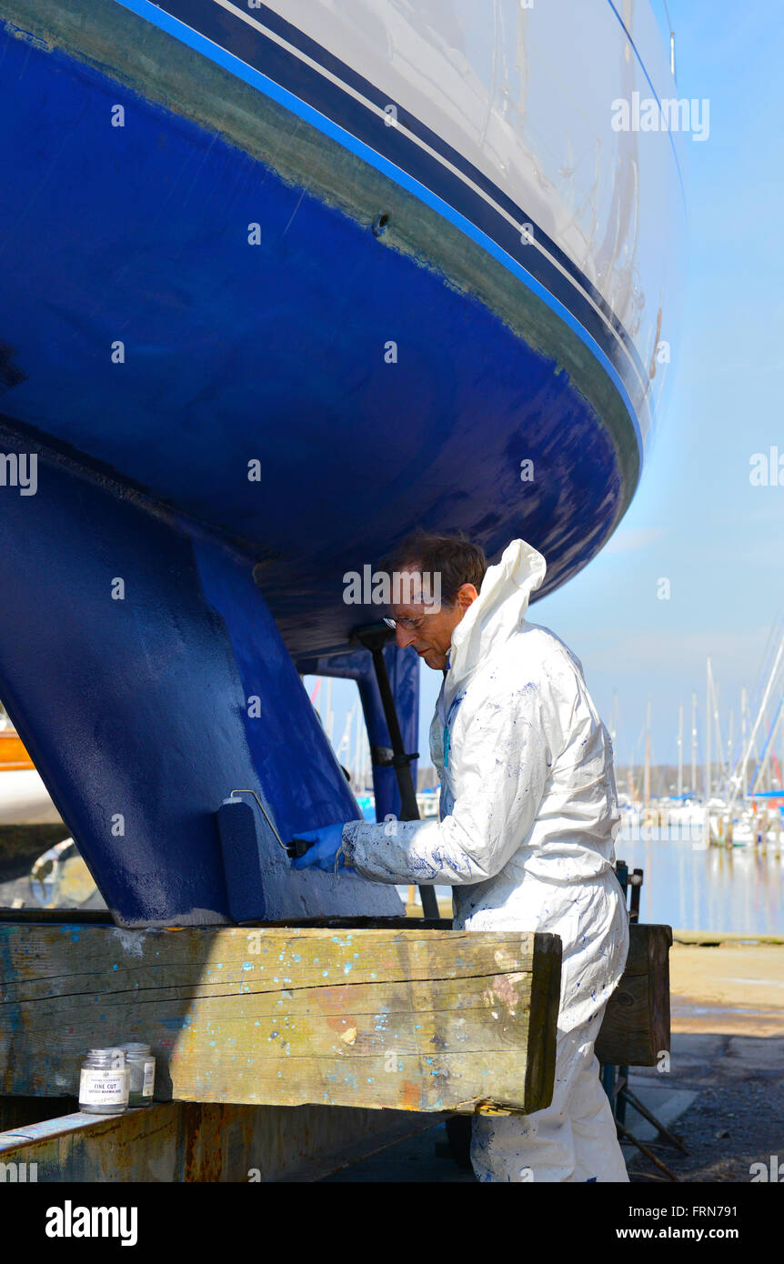 Der Bootsbesitzer, der seine zweikegelige Yacht mit einer Walze (Seewegenprägung) abkeucht und sich auf die neue Segelsaison vorbereitet. West Sussex, Großbritannien Stockfoto