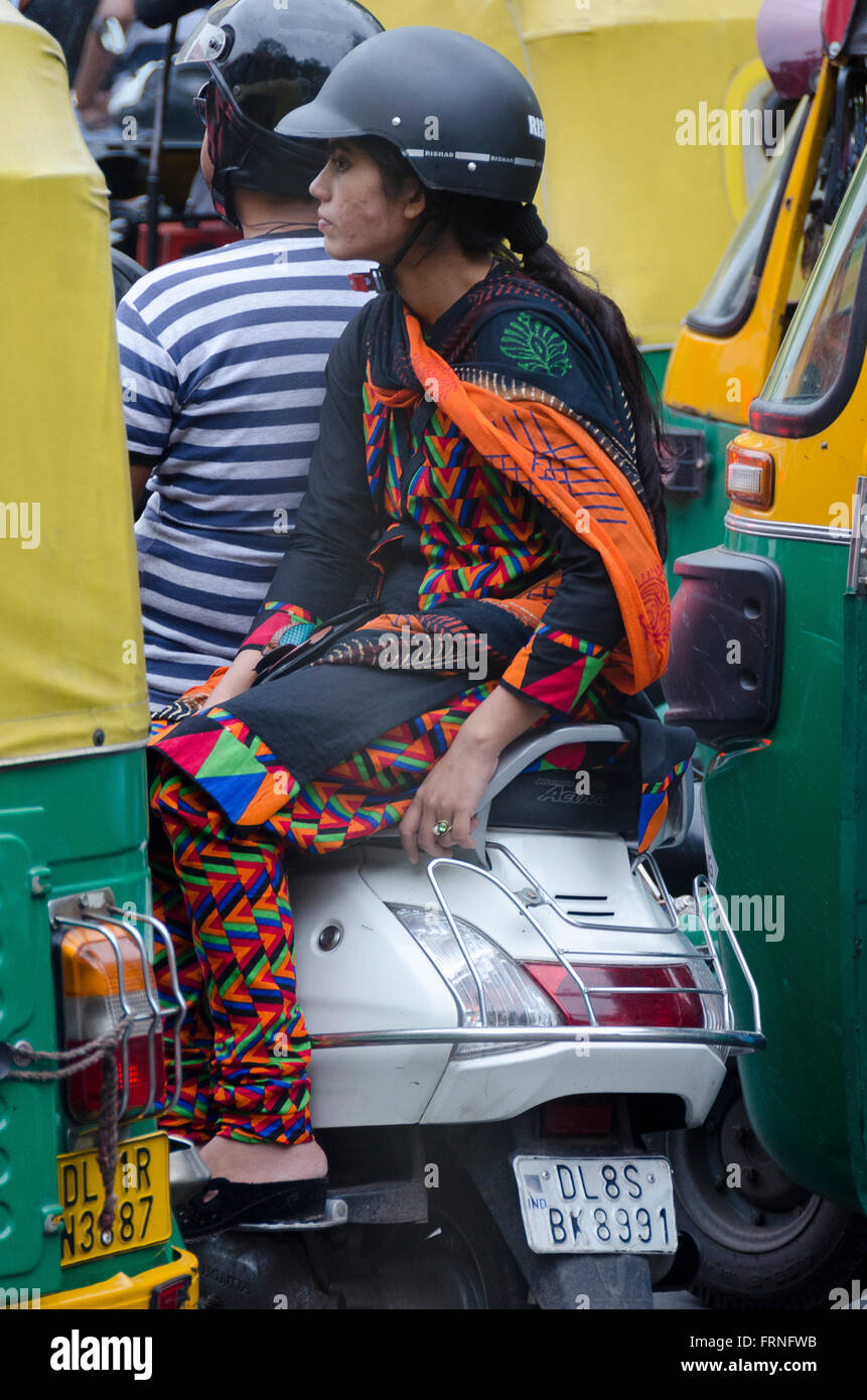 Paar auf Motorroller im Verkehr mit Tuk Tuks, Delhi, Indien Stockfoto