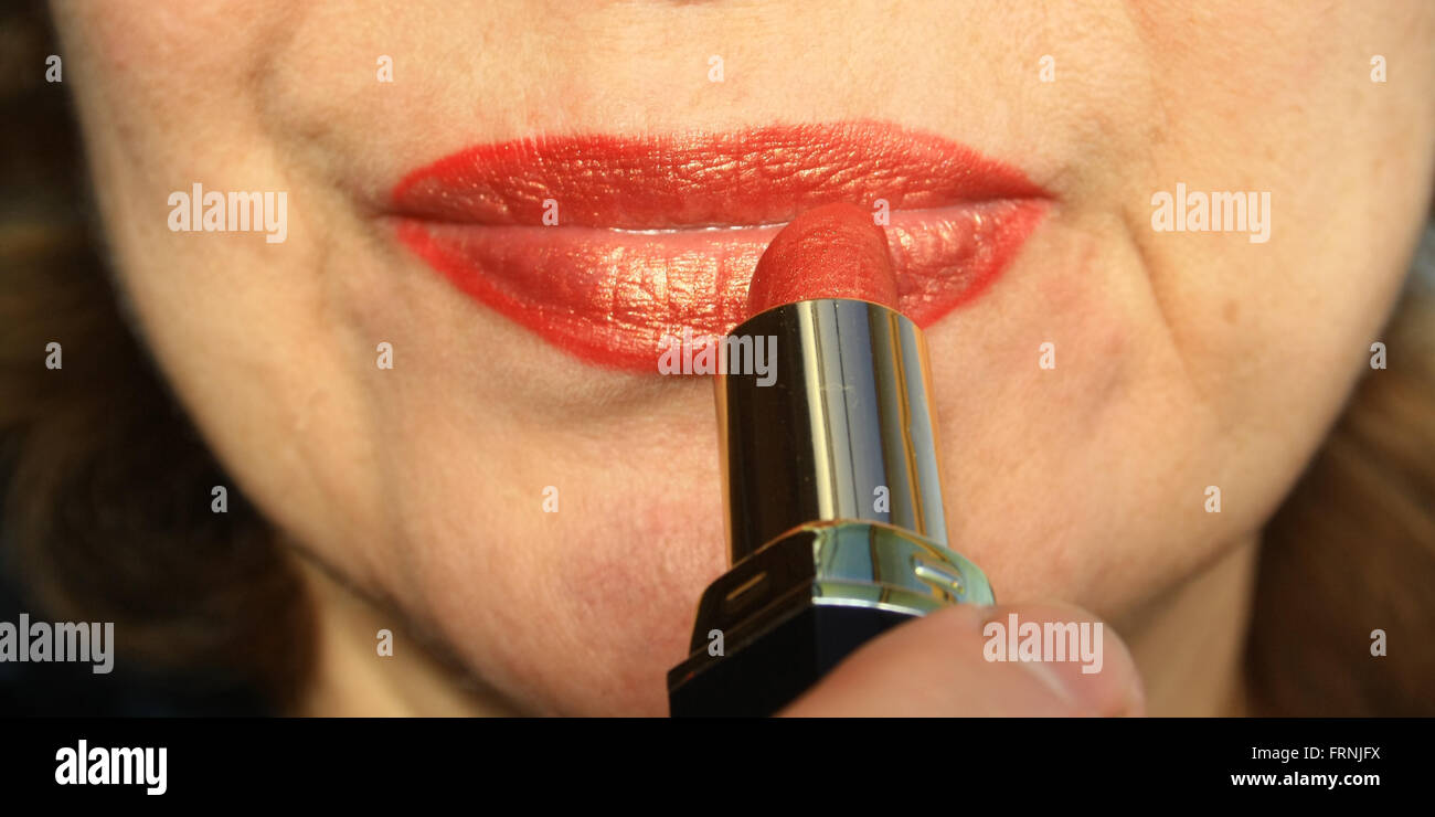 Frau malt Lippen mit rotem Lippenstift Stockfoto