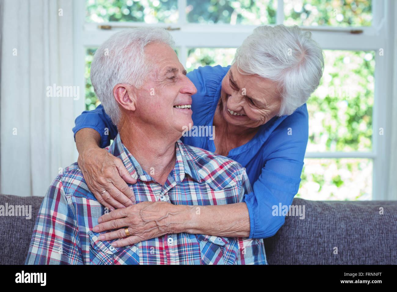 Fröhliche Frau, die beim betrachten senior Mann umarmt Stockfoto