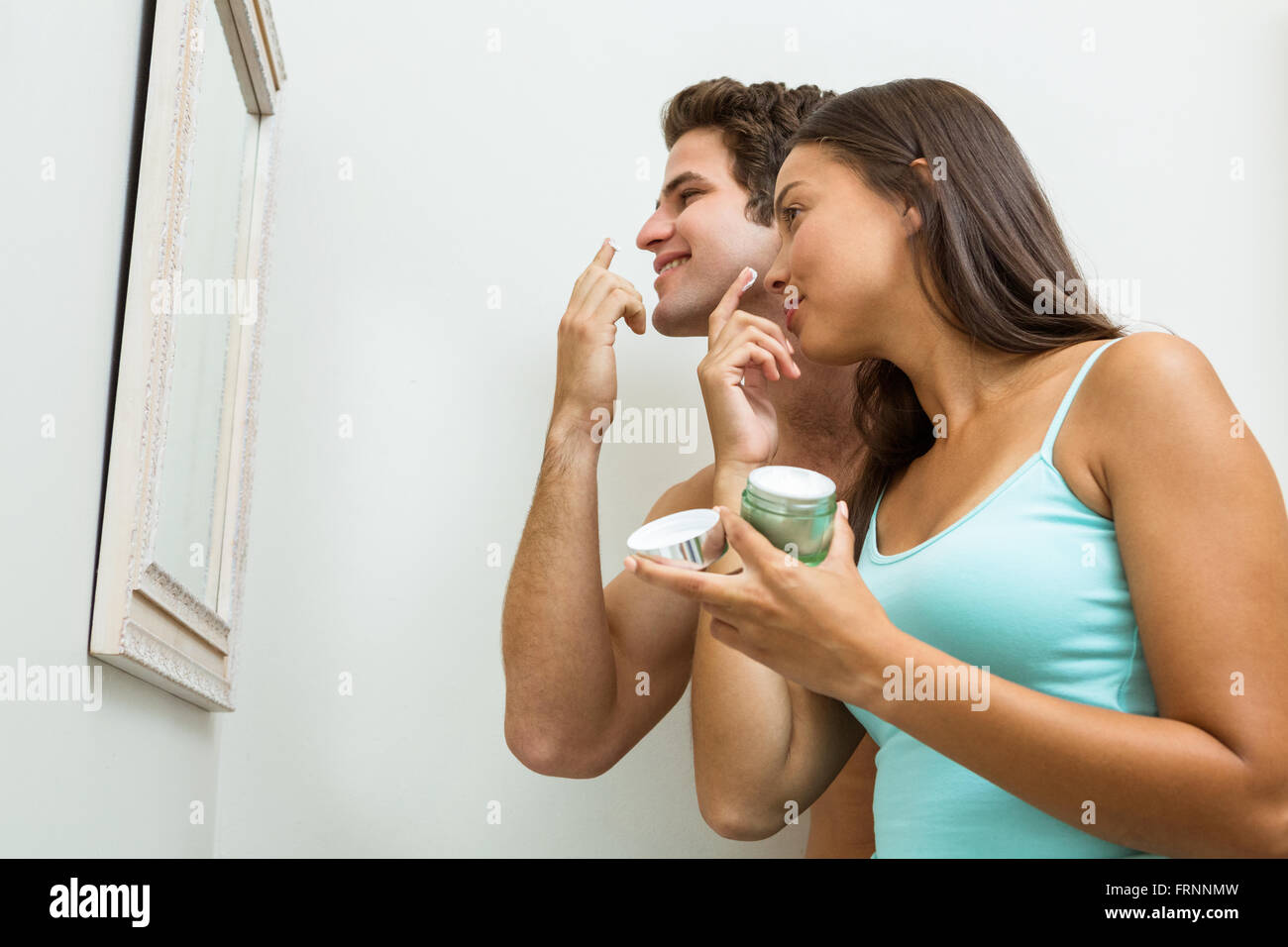 Junges Paar anwenden Feuchtigkeitscreme auf ihrem Gesicht Stockfoto