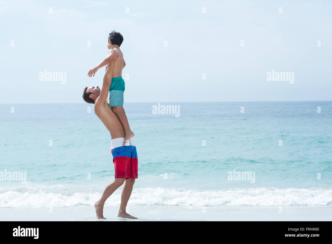 Vater mit Sohn beim Stehen am Strand Stockfoto