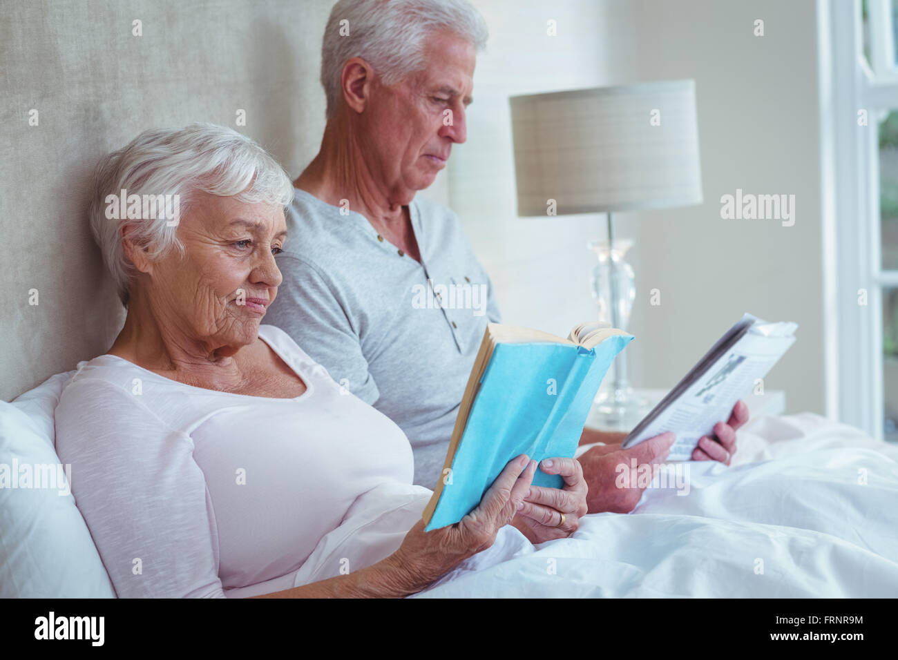 Älteres paar Lesebuch auf Bett Stockfoto