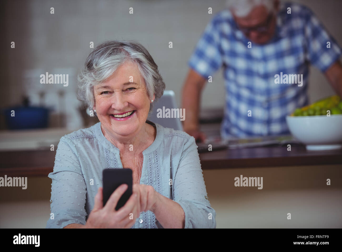 Porträt von senior Frau mit Telefon in Küche Stockfoto