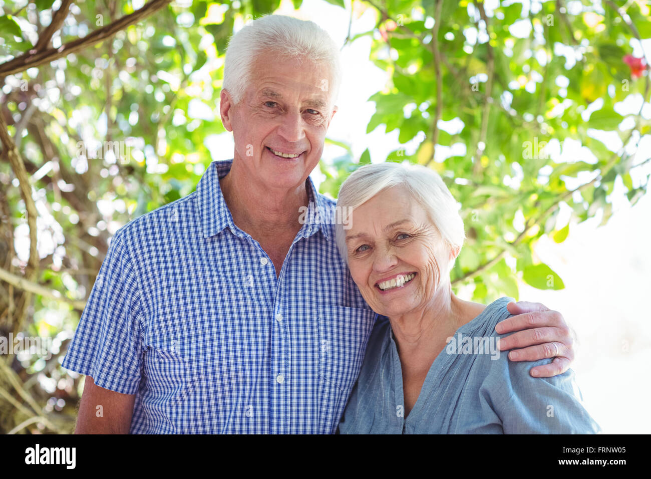 Älteres Paar mit Arm um lächelnd Stockfoto