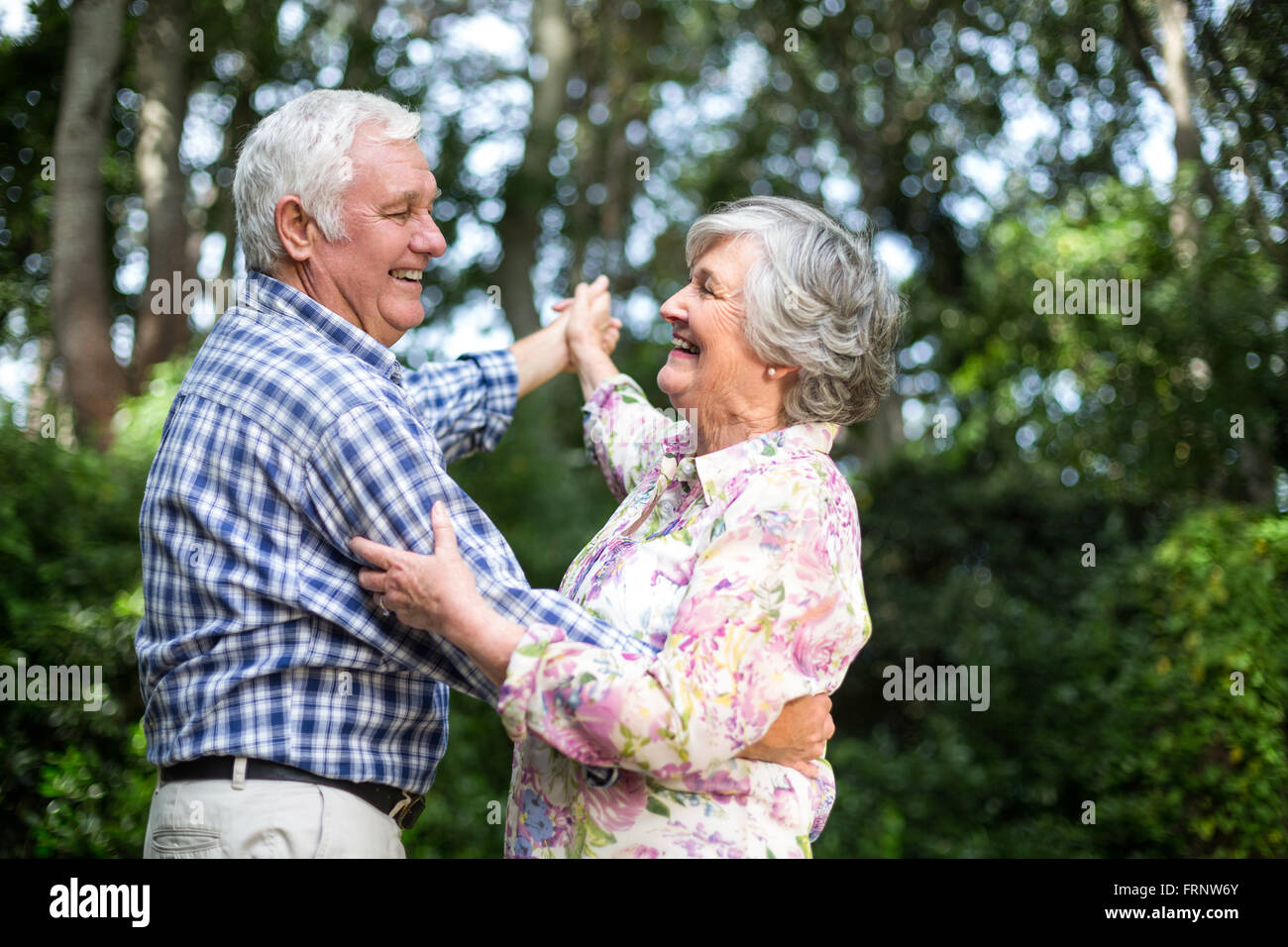 Fröhliche Senioren Paare tanzen gegen Bäume Stockfoto