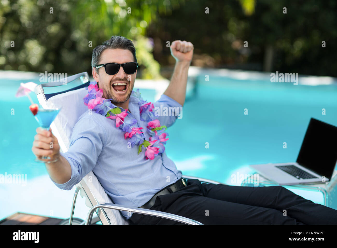 Aufgeregt Mann trägt Girlande und hält ein Martini-Glas Stockfoto