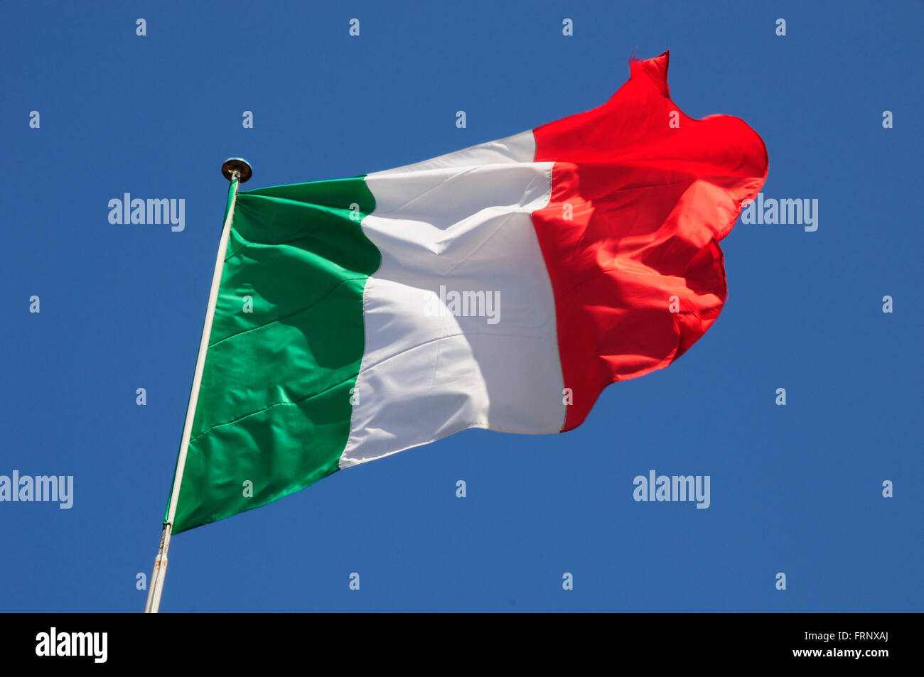 Italienische Flagge flattern in einer lebhaften Brise gegen ein strahlend blauer Himmel. Stockfoto
