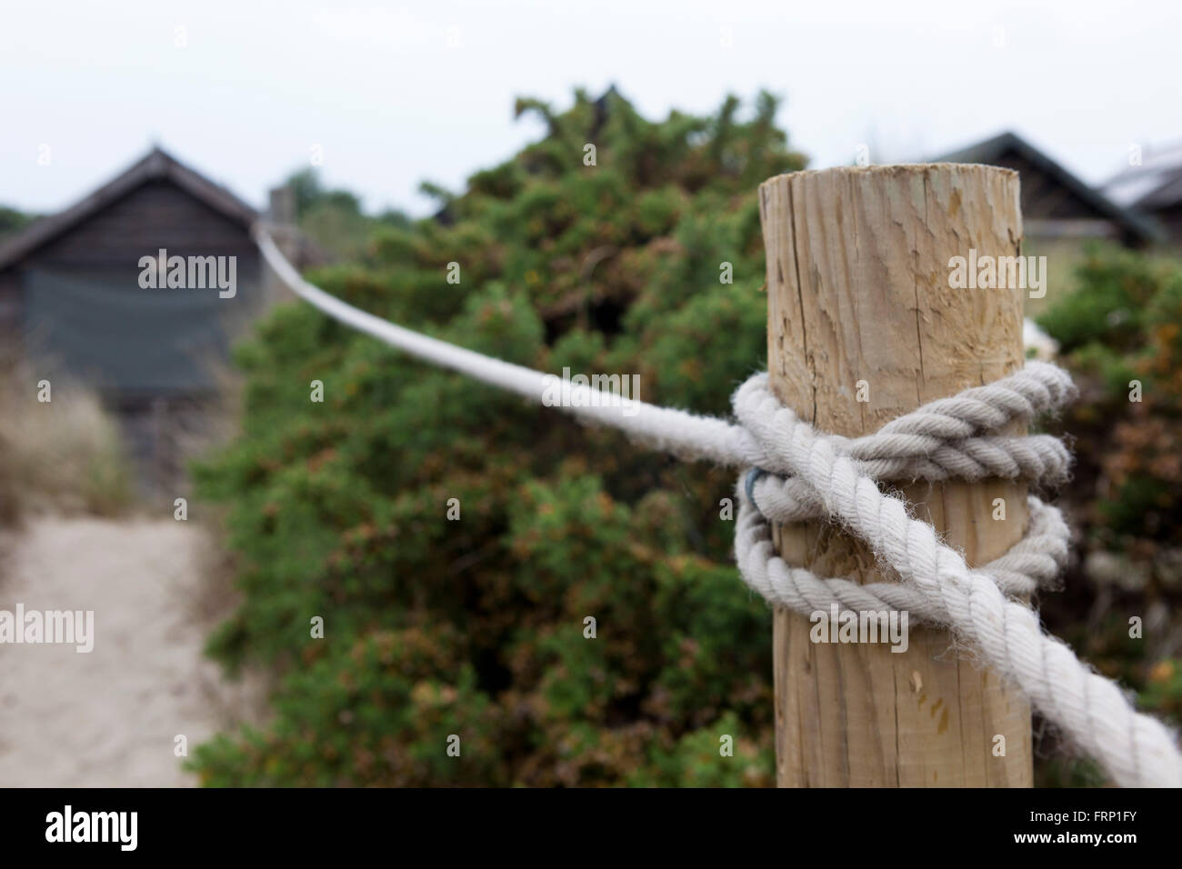 Einen hölzernen Pfosten und Seil Zaun zeichnen Sie einen Pfad durch die Dünen zum Strandhütten an der Küste von Dorset, UK. Stockfoto