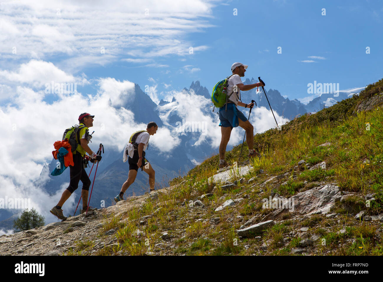 Drei Teilnehmer des UTMB laufen in den Hügeln von Chamonix. Im Hintergrund sind die berühmten Gipfel des Mont-Blanc-Massiv. Stockfoto