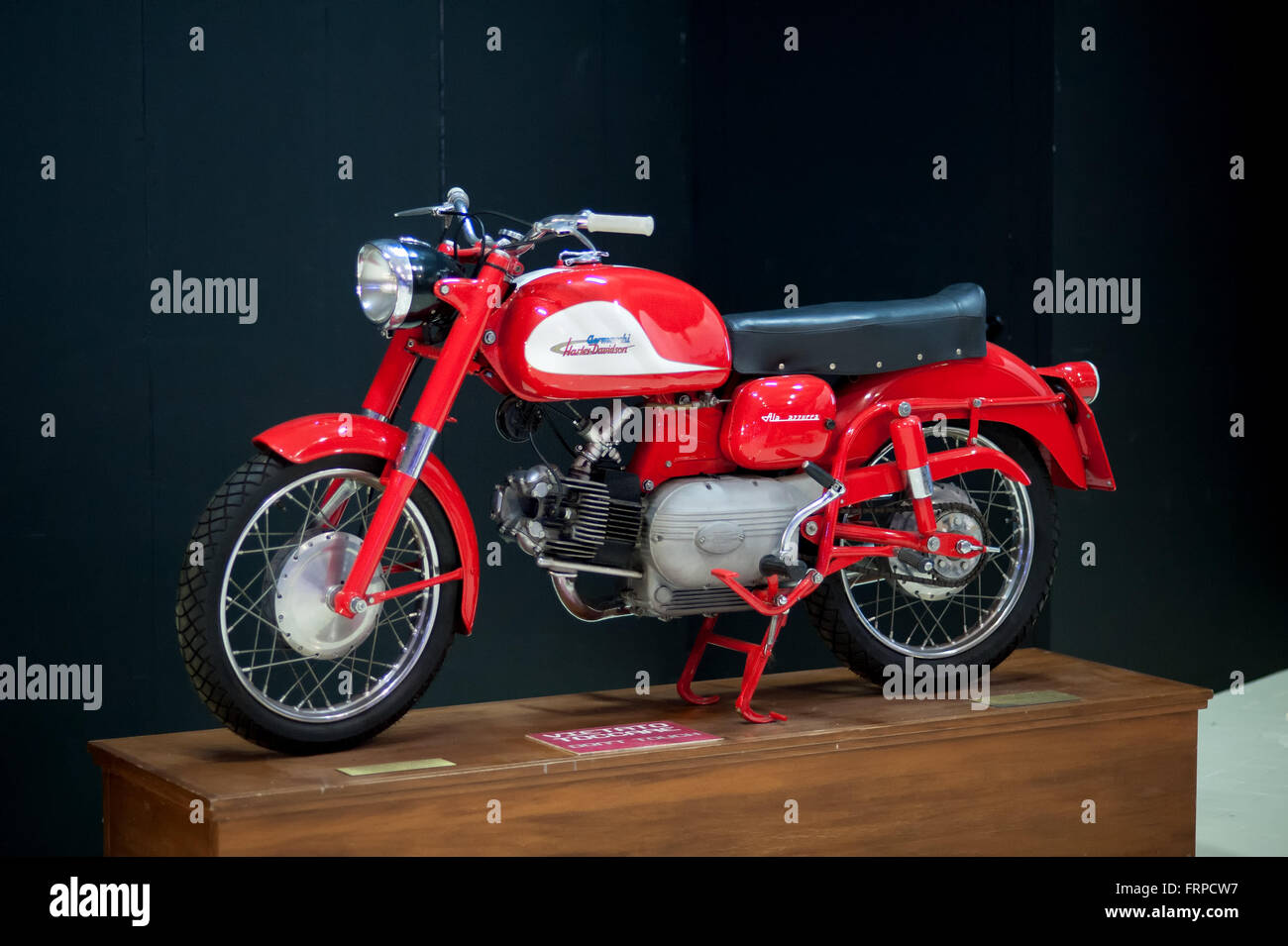 Einzelnes alte altmodisches rotes und weißes Harley Davidson - Aermacchi Motorrad auf hölzernen Display stellen Sie sich vor schwarzem Hintergrund Stockfoto